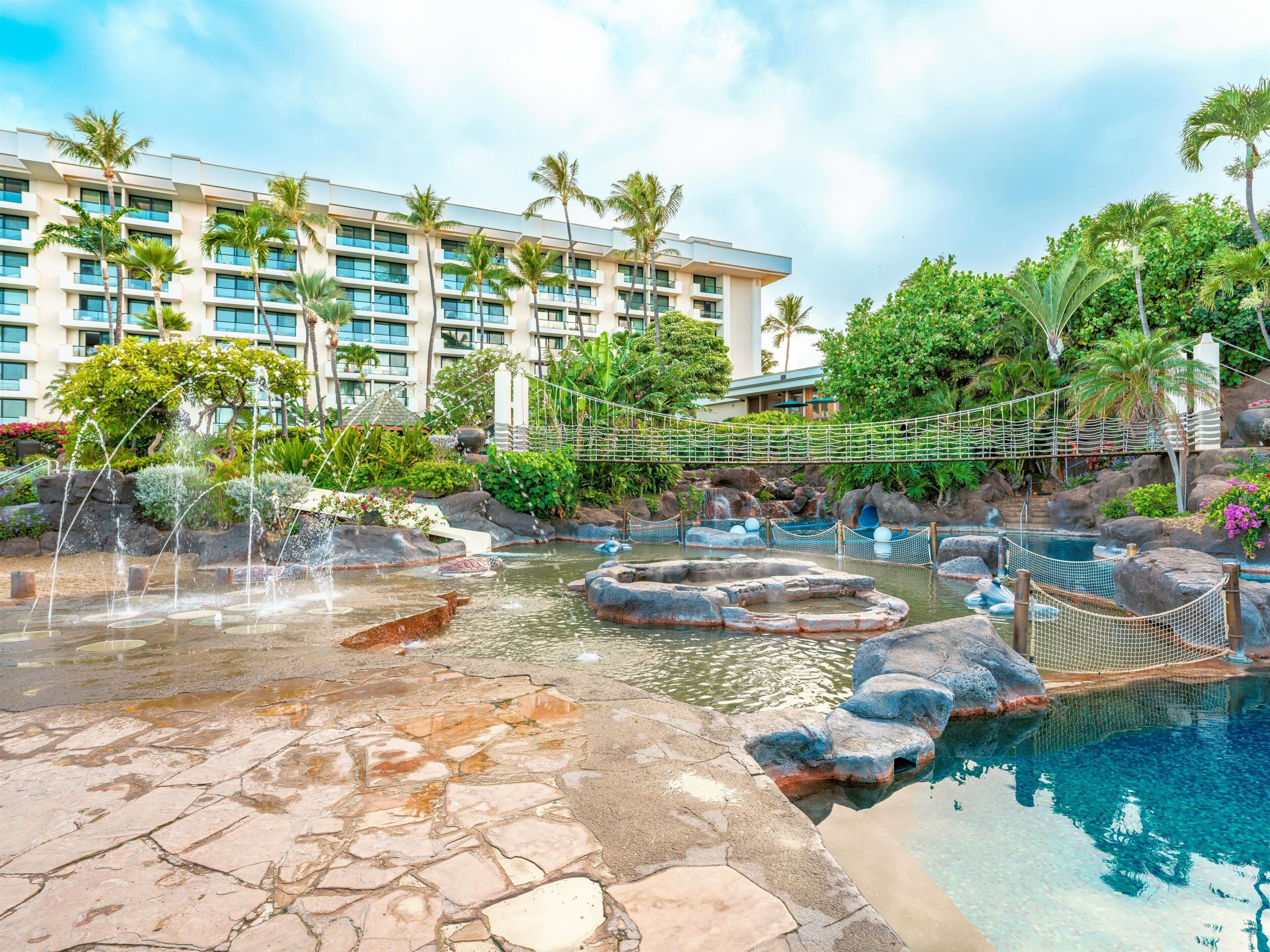 Un resort con piscina, un puente y un edificio de varios pisos.