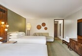 A hotel room with two beds, a sofa, a desk, and a TV.