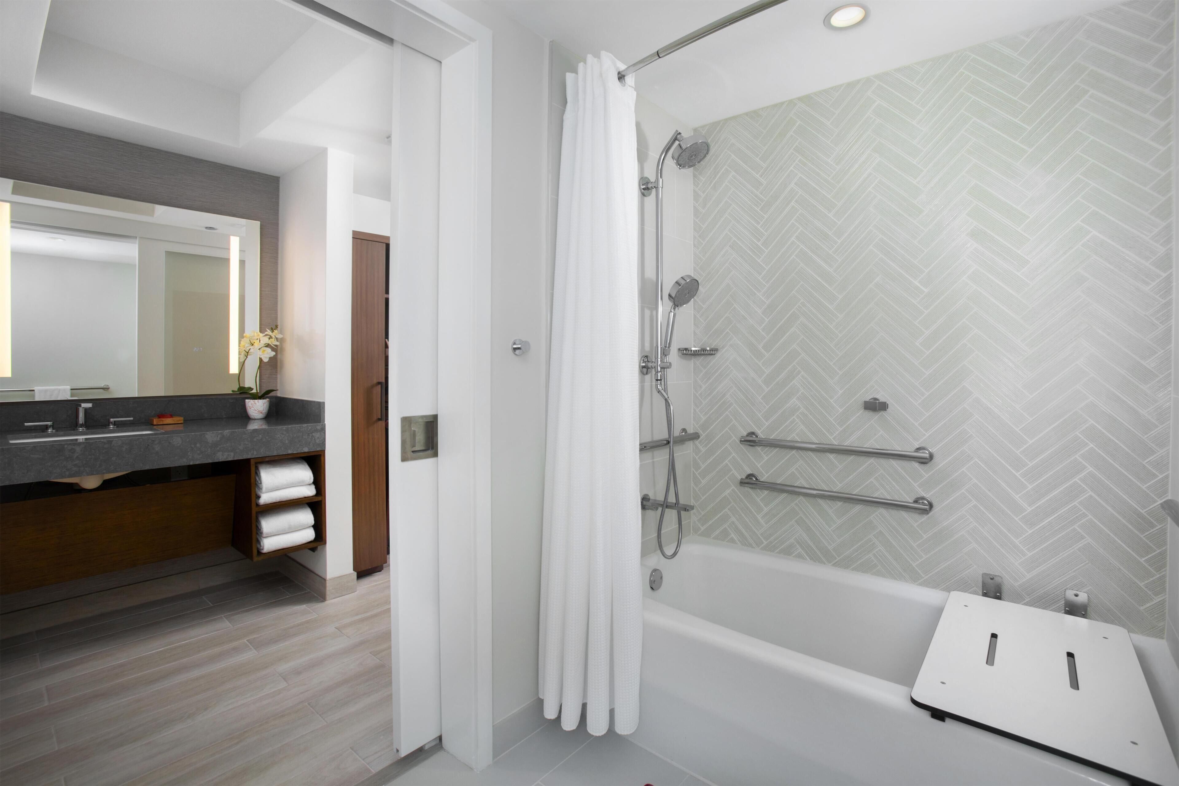 A modern bathroom with a shower, a bathtub, and a vanity with a mirror.