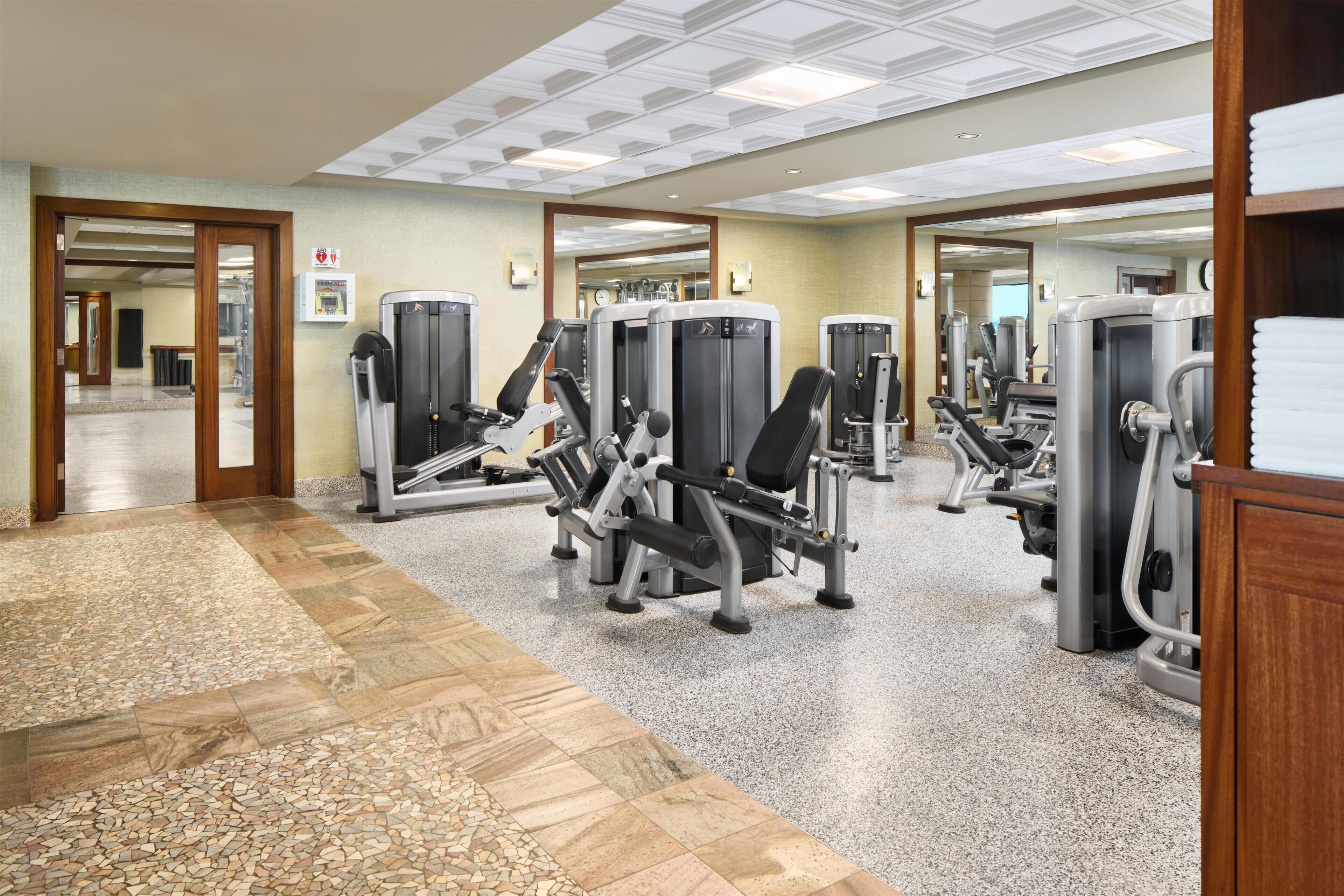 A gym with various exercise machines, a mirrored wall, and a patterned floor.