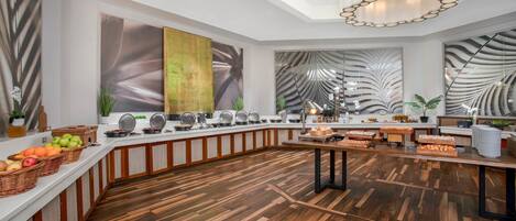 A modern kitchen with a wooden floor, a buffet setup, and a large window.
