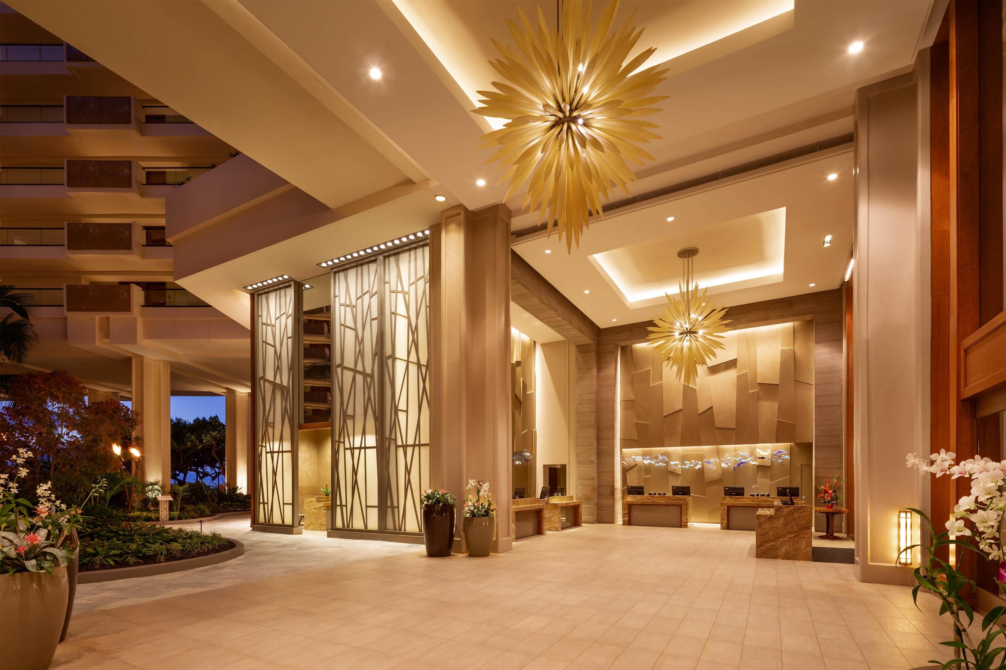 A spacious lobby with a reception desk, modern lighting fixtures, and a view of the building's exterior.