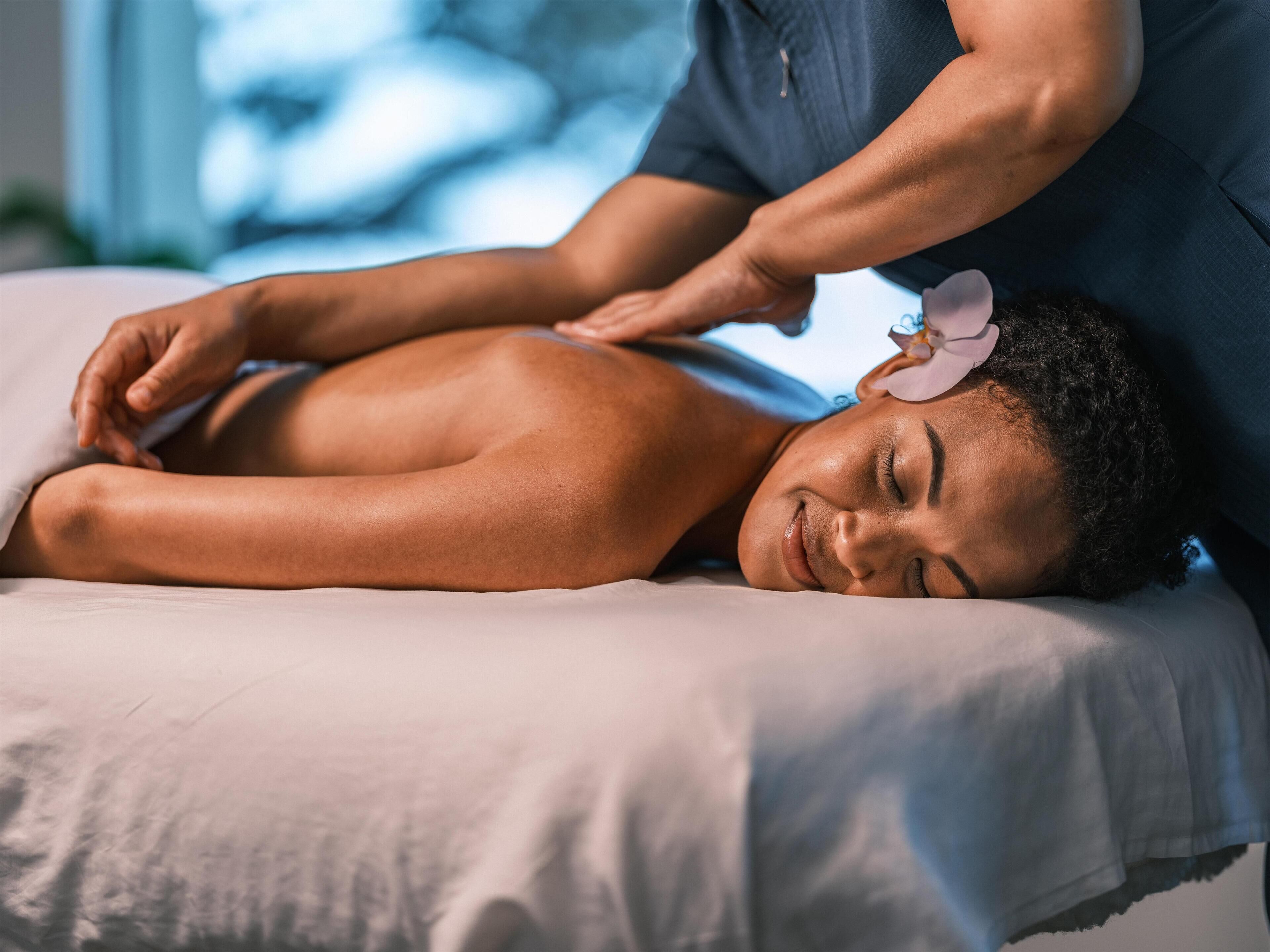 A person receiving a back massage on a bed with a pillow.