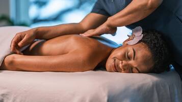 A person receiving a back massage on a bed with a pillow.