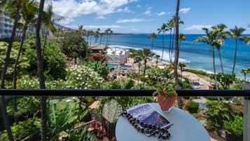 Un balcón con vista a una playa, palmeras y un jardín tropical.