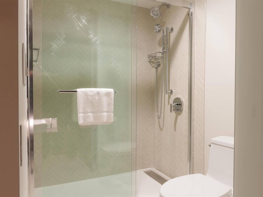 Un baño con ducha de vidrio, inodoro y perchero para toallas.