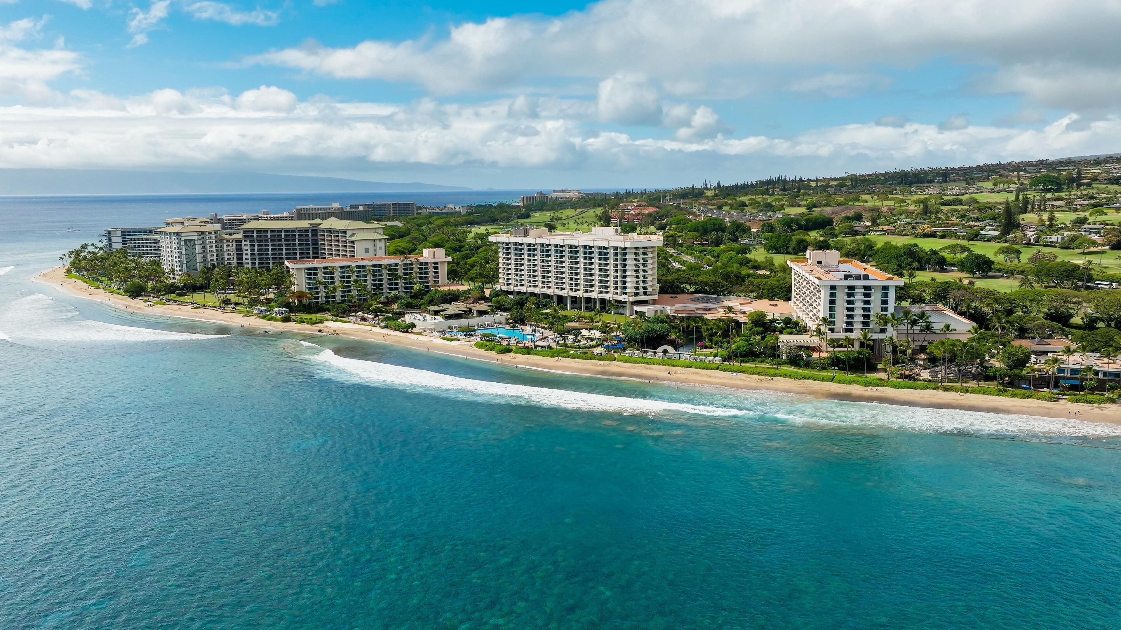 A coastal resort with beachfront properties, a pool area, and lush greenery.