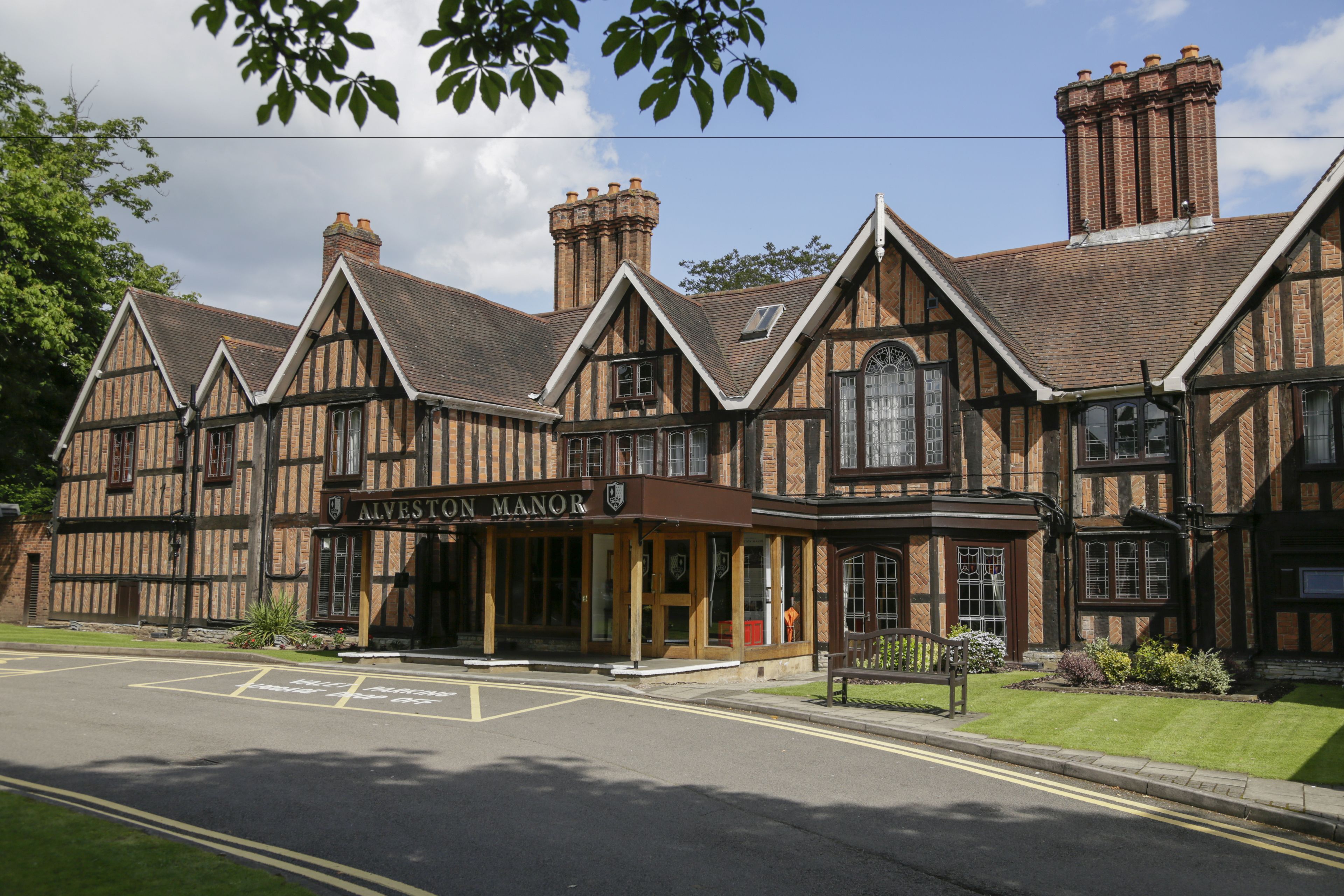 A traditional Tudor-style building with a sign reading "Alveston Manor."