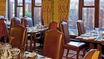 A dining area with tables set for multiple guests, featuring a traditional layout with chairs and dining tables.