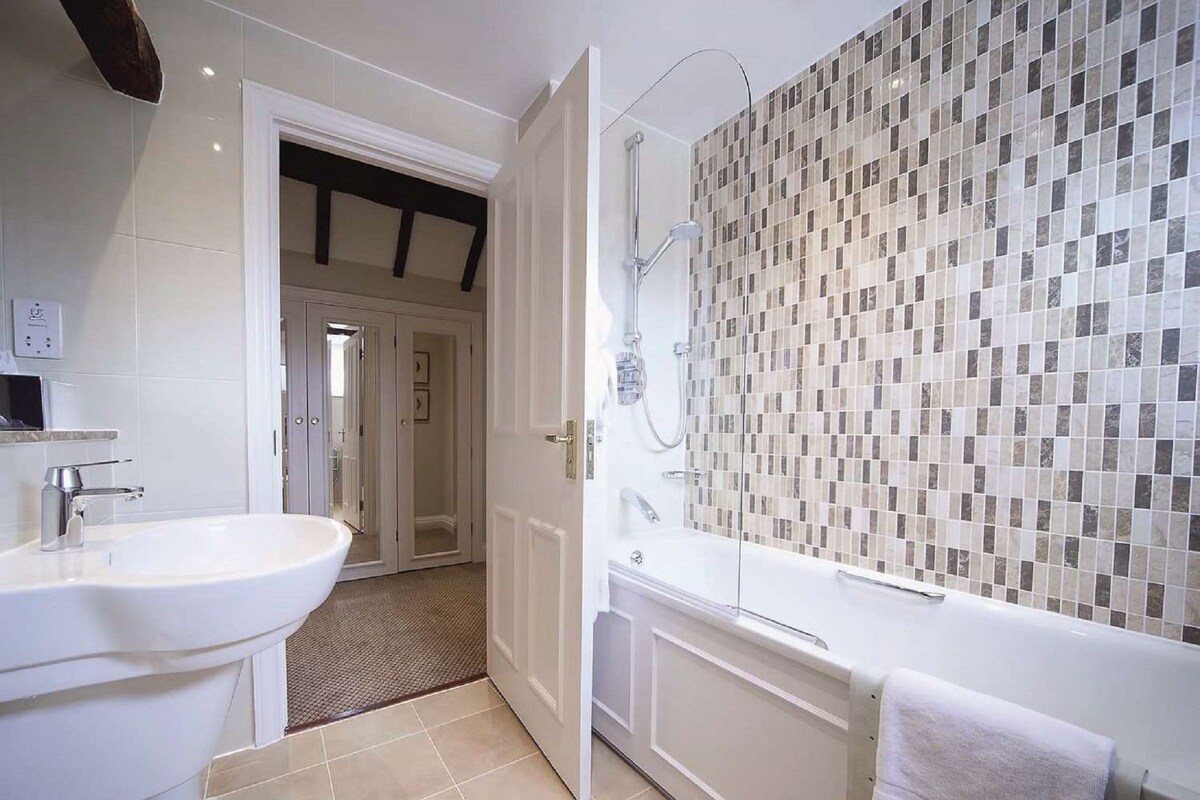 Een badkamer met een groot wastafel, een douche en een betegelde muur.