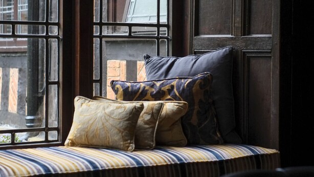 A window seat with cushions, a view of a building, and a door.