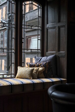 A window seat with cushions, a view of a building, and a door.
