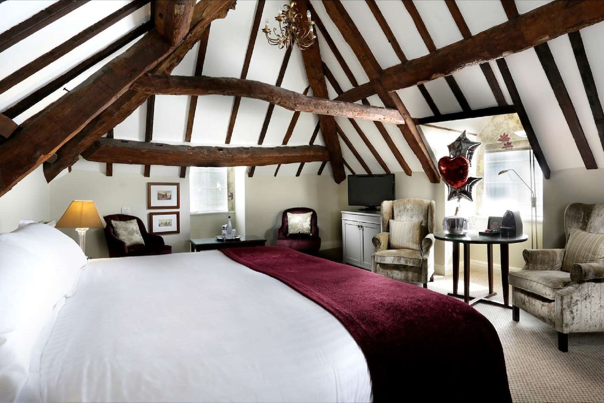 Een slaapkamer met een groot bed, een bureau, een stoel en een televisie.