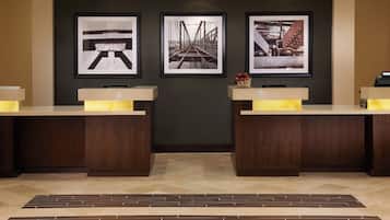 A reception area with two reception desks, a herringbone-patterned floor, and three framed photographs on the wall.