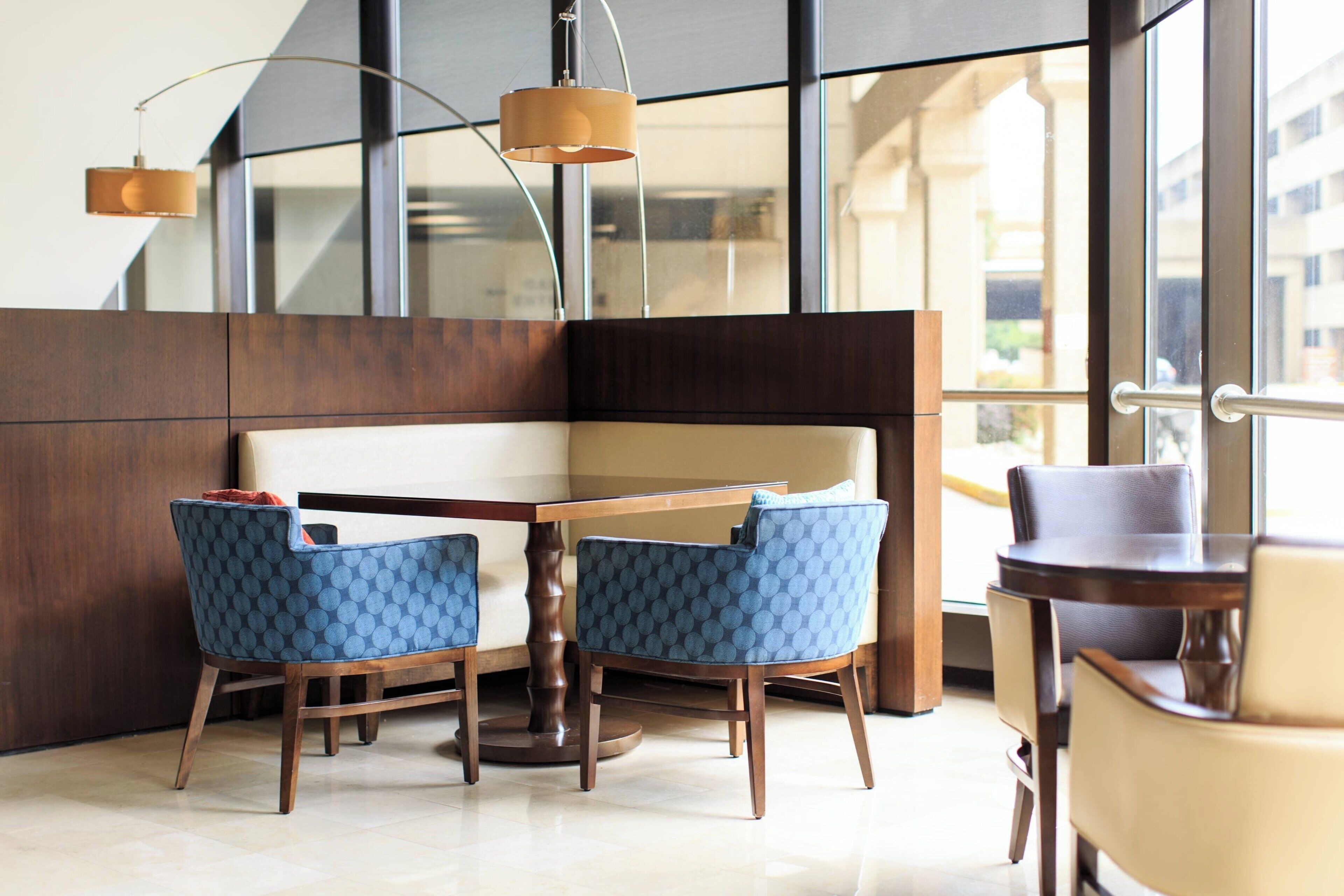 Un espace repas moderne avec une table en bois et deux chaises bleues à motifs, un banc en bois et une suspension.