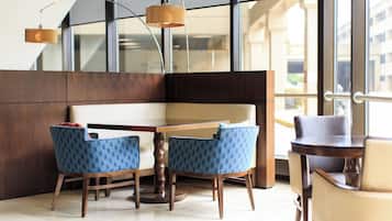 Een moderne eethoek met een houten tafel, twee blauw gestreepte stoelen, een houten bank en een hangende hanglamp.