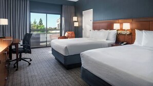 A hotel room with two beds, a desk, a chair, and a view of the outdoors. - Courtyard by Marriott Phoenix Airport (Phoenix)