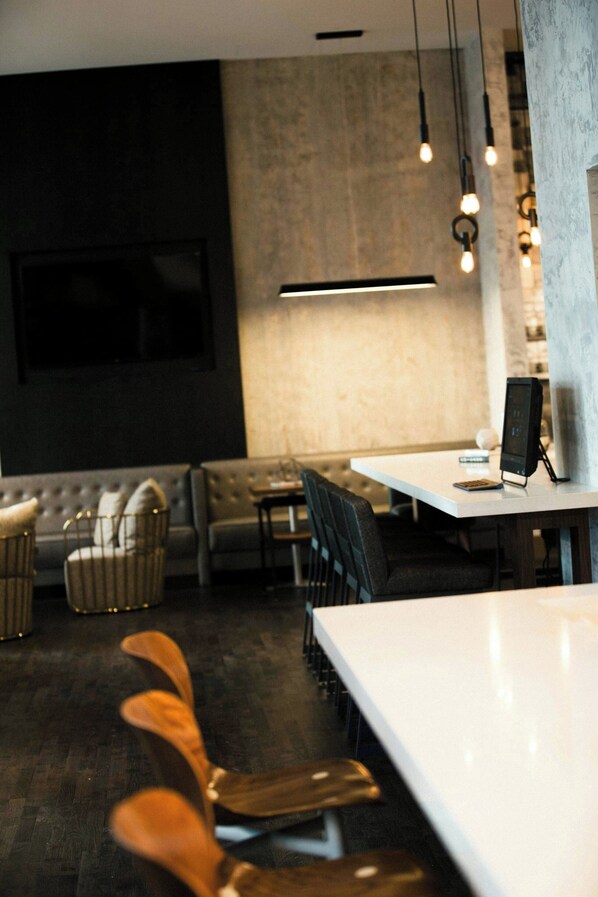 Un comedor moderno con una mesa blanca, sillas de madera oscura y una zona de bar con taburetes.
