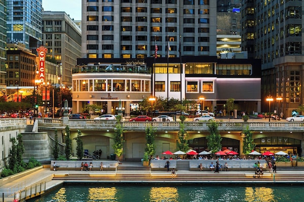 A riverside hotel with outdoor seating, a view of the river, and a prominent 'CITY' sign.