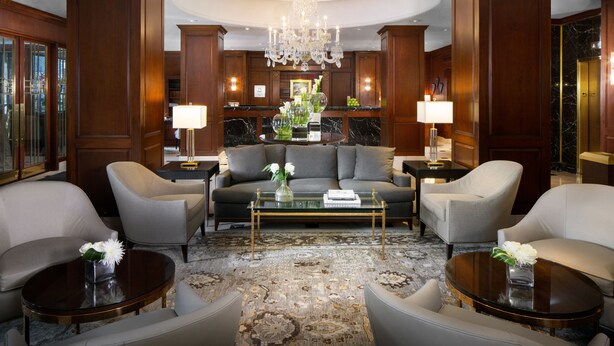A luxurious lobby with a grand chandelier, plush seating, and a marble floor.