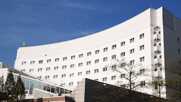 Um edifício moderno com fachada curva, várias janelas e entrada de vidro.