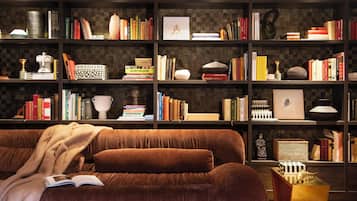 A cozy reading area with a brown sofa, a bookshelf filled with books, and decorative items.