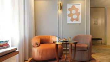 Una sala de estar moderna con un sofá, un sillón y una mesita redonda con un jarrón y un libro.