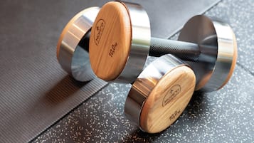 A set of adjustable dumbbells with wooden handles and metallic weights, placed on a textured surface.