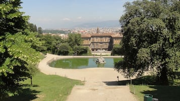 A view of a historic building with a central courtyard and a pond.