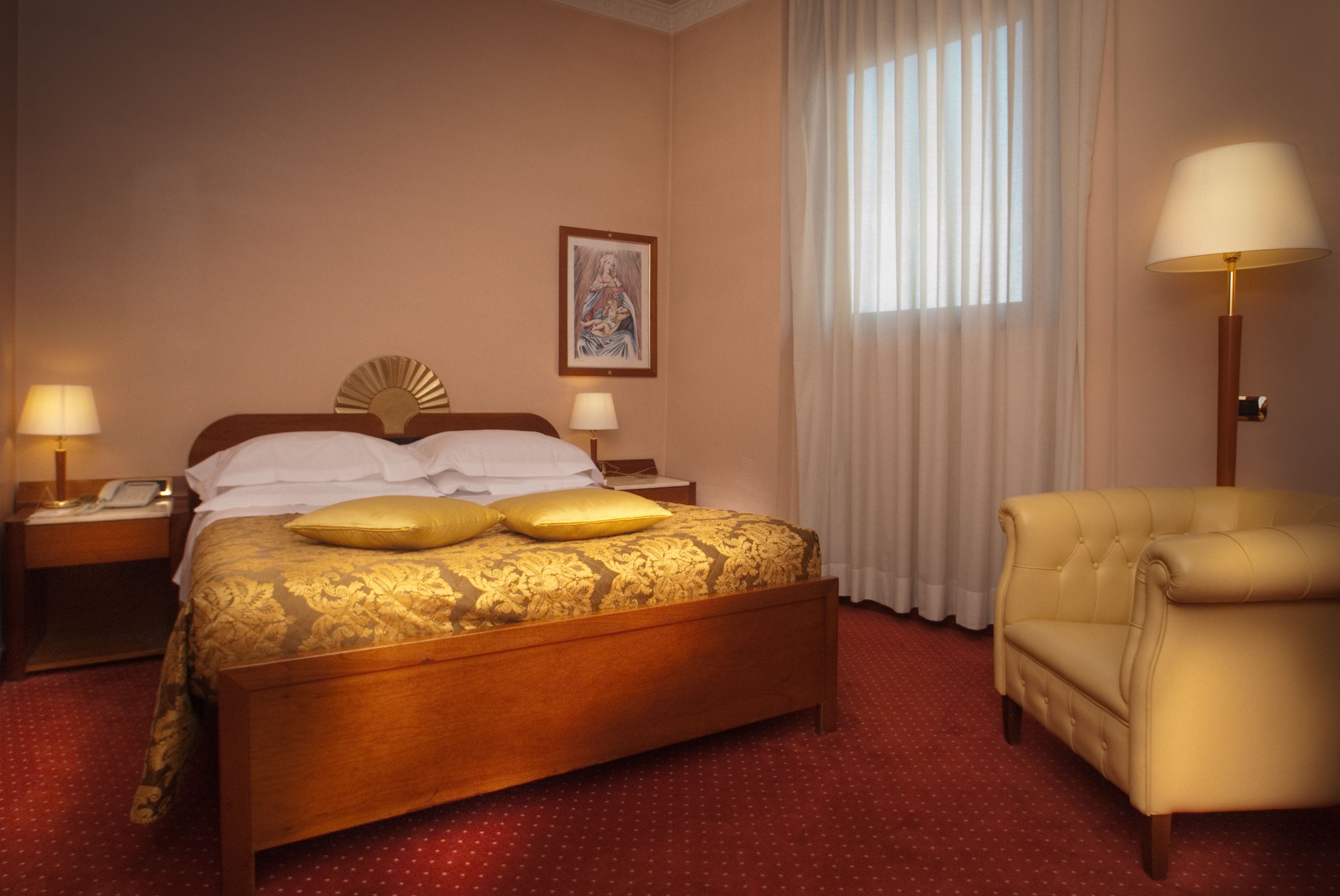 Une chambre d’hôtel avec un lit en bois, deux lampes de chevet, une chaise et une fenêtre avec des rideaux.