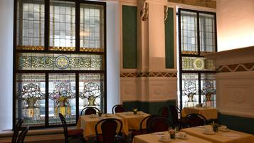 A dining area with tables set for service, large stained glass windows, and classic interior design.