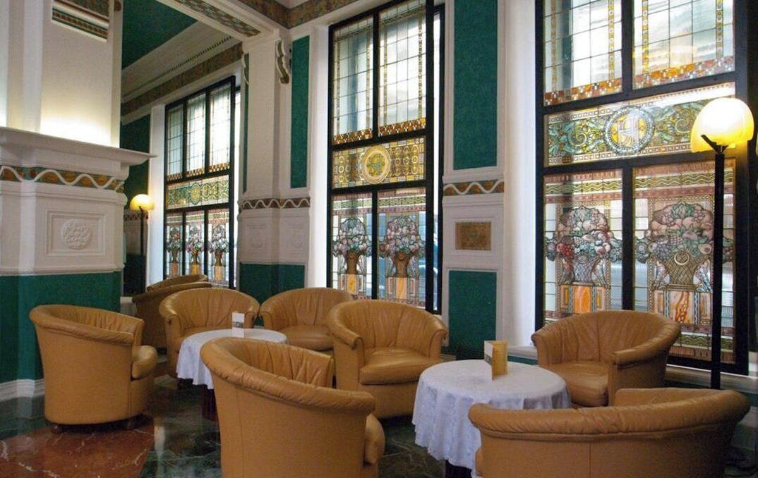 A room with large windows, leather chairs, and a chandelier.