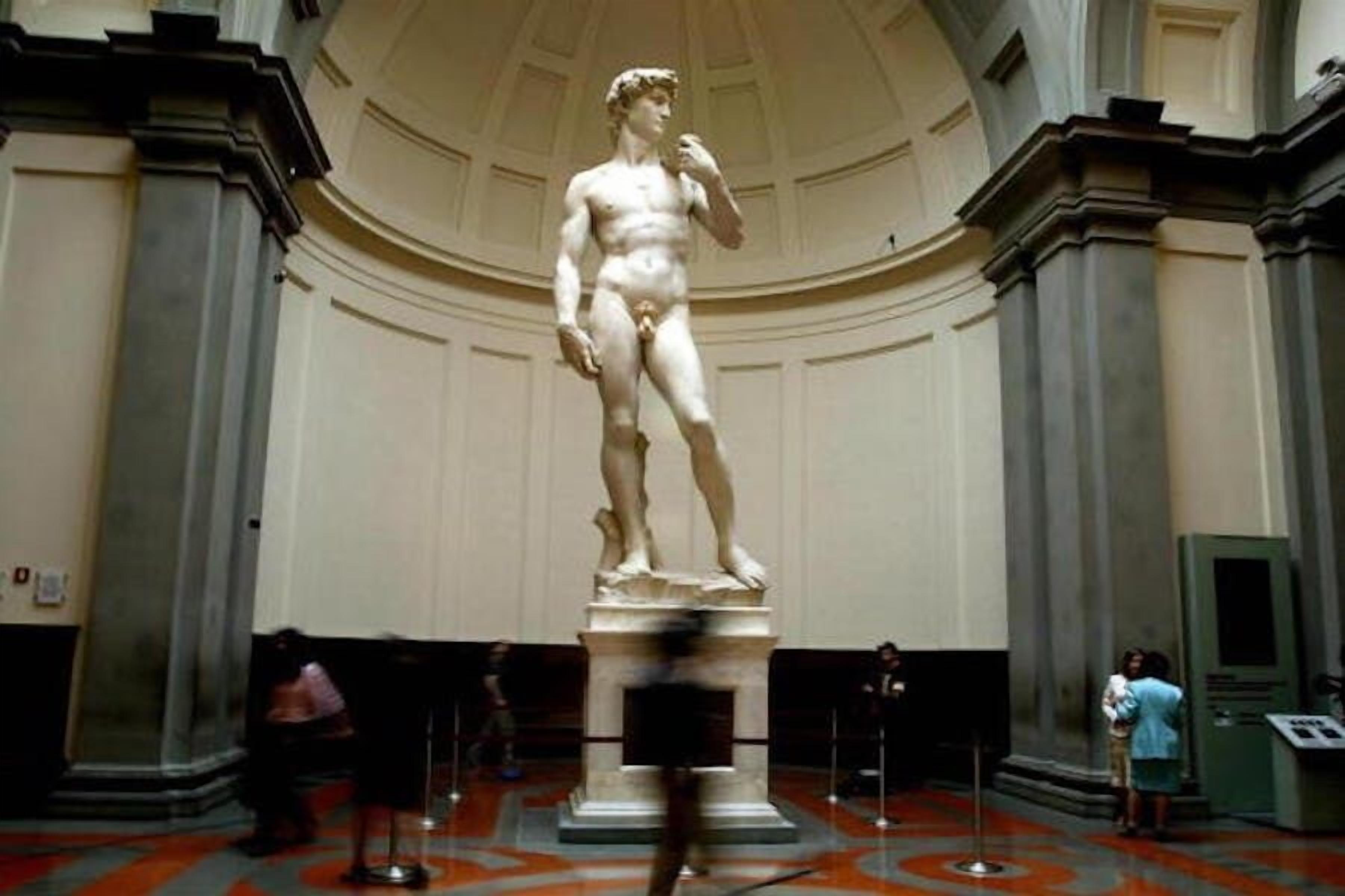 A marble statue in a museum with a domed ceiling and columns.