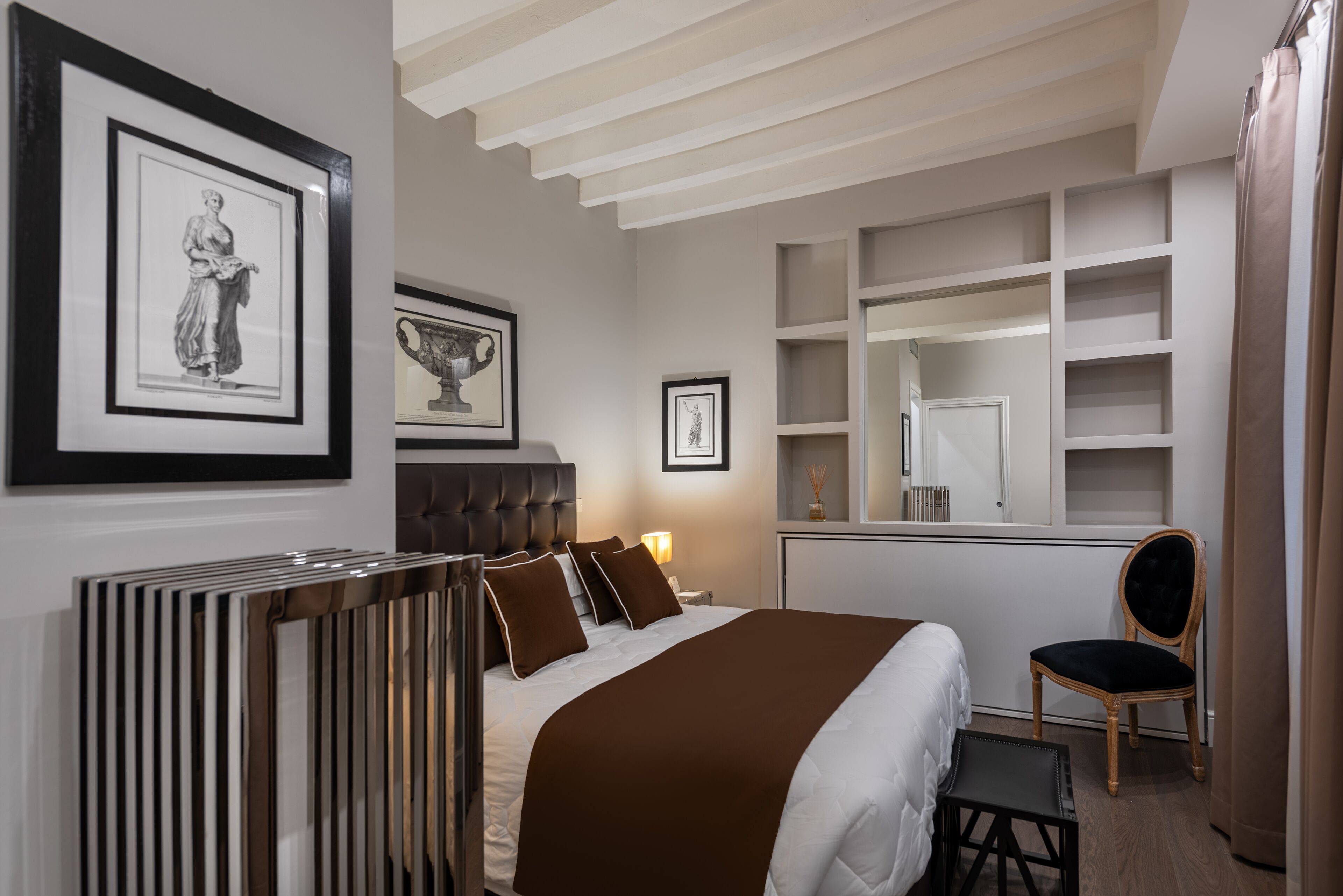 Une chambre d’hôtel moderne, dotée d’un grand lit, d’une commode, d’une coiffeuse avec un miroir et de tableaux encadrés aux murs.