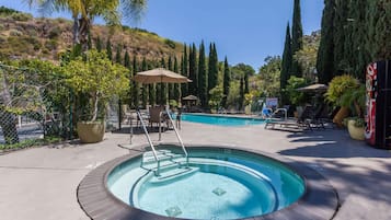 Relax by the pool surrounded by lush greenery and comfortable lounge chairs.