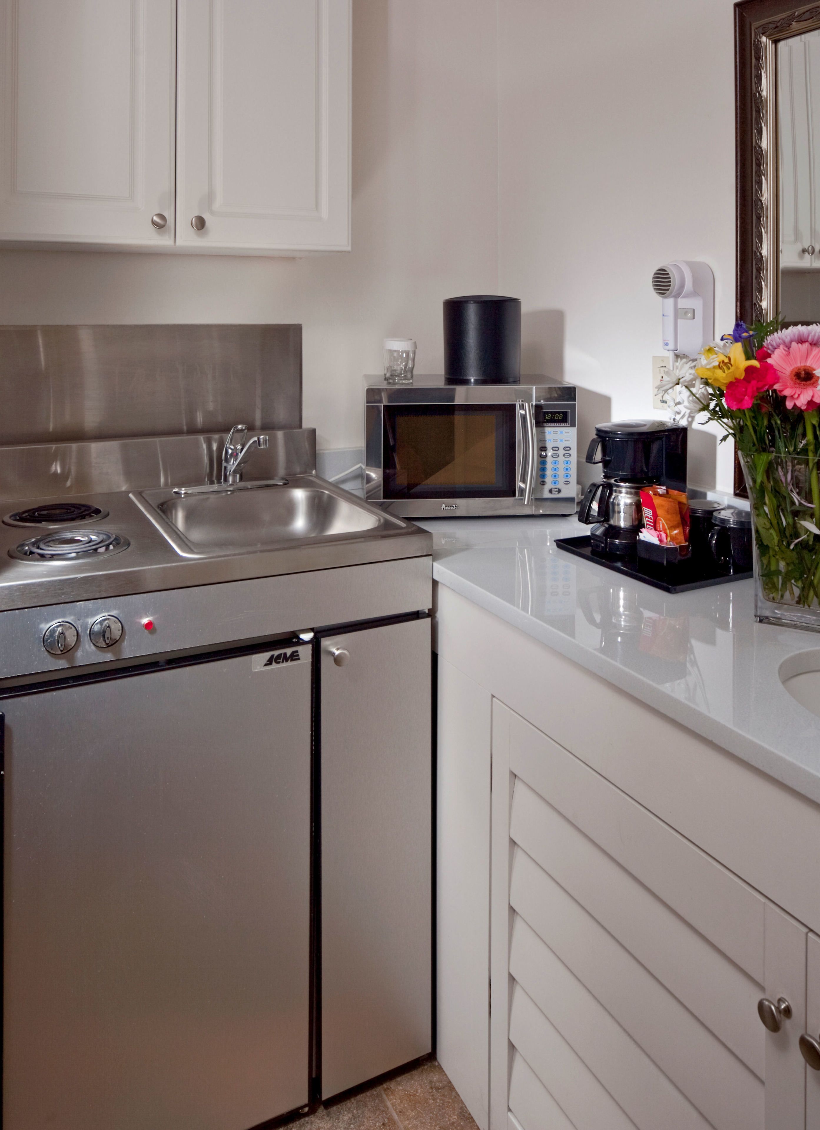 Une cuisine compacte équipée d’une cuisinière, d’un four à micro-ondes et d’une machine à café.