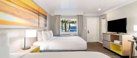 A hotel room with a large bed, a TV, a desk, and a painting on the wall.