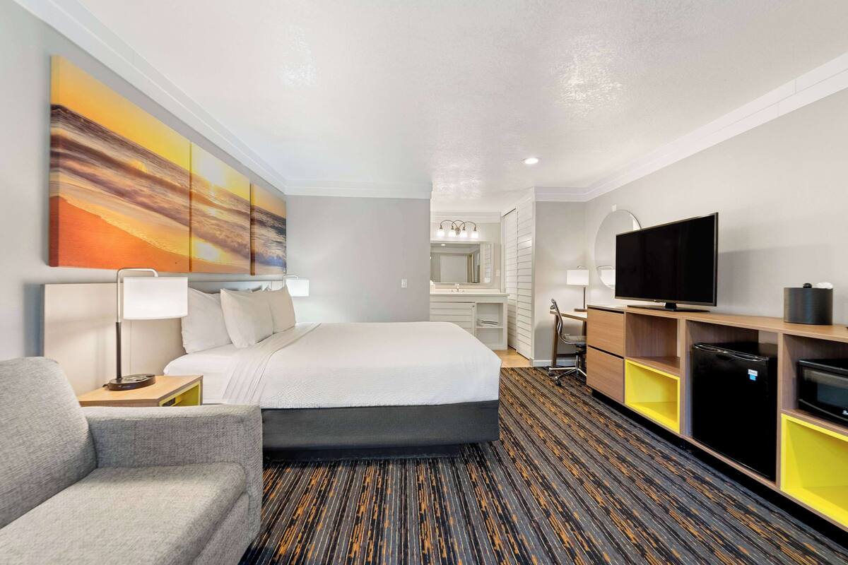 Ein Hotelzimmer mit Bett, Schreibtisch, Fernseher und Kühlschrank.