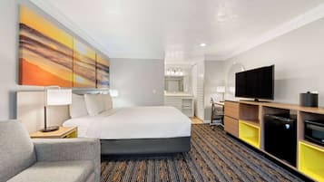 Une chambre d’hôtel équipée d’un lit, d’un bureau, d’une télévision et d’un réfrigérateur.