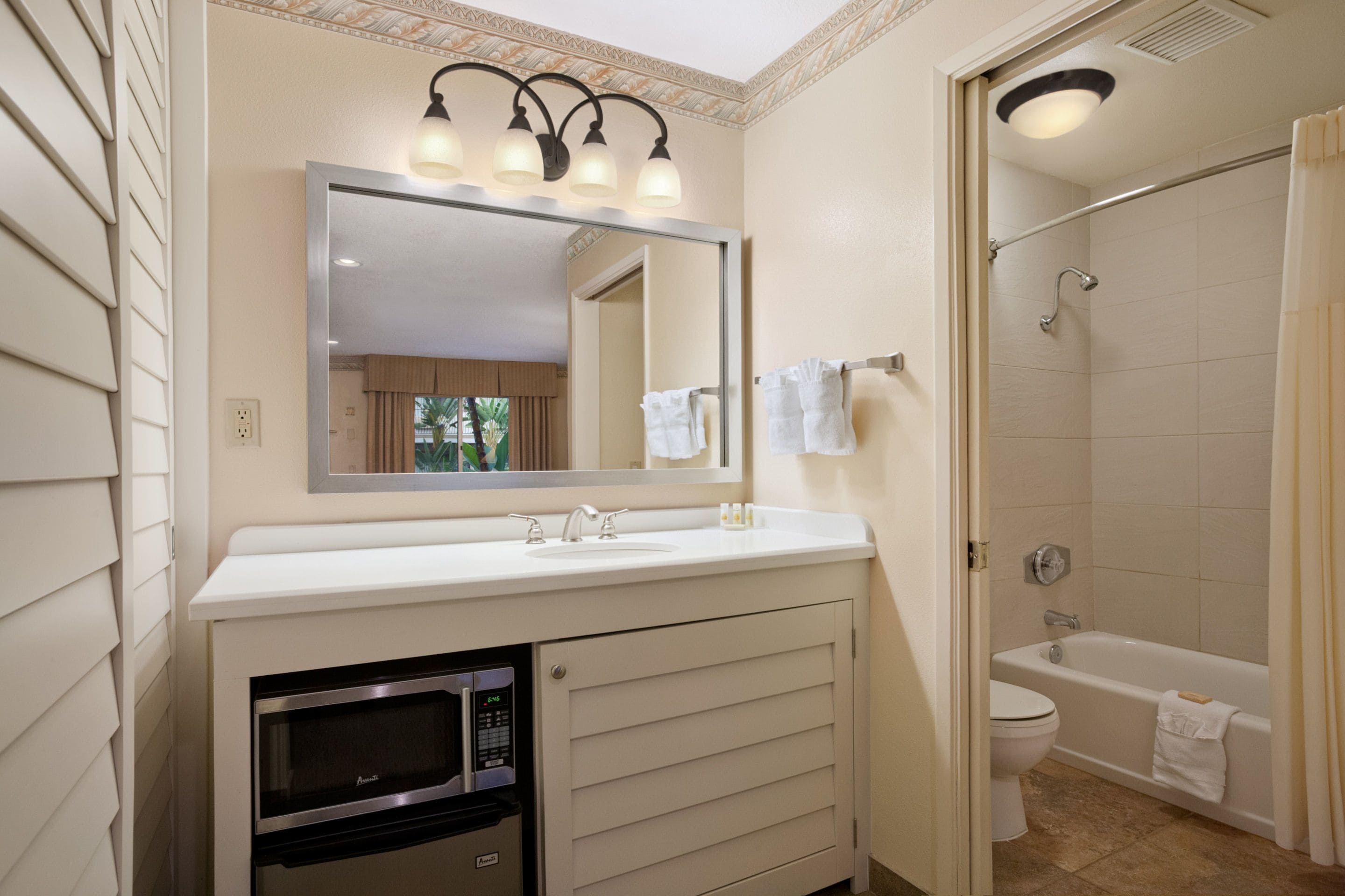 A bathroom with a sink, mirror, and shower.