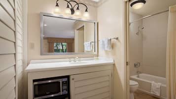 A bathroom with a sink, mirror, and shower.