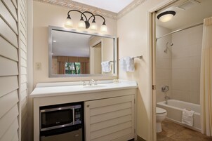 A bathroom with a sink, mirror, and shower.