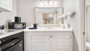 Cocina compacta equipada con microondas, cafetera y lavabo.