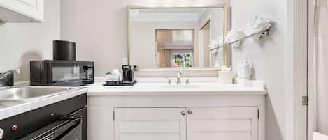 A compact kitchen with a microwave, coffee maker, and sink.