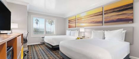 A hotel room with two beds, a desk with a TV, a window with a view, and a painting on the wall.