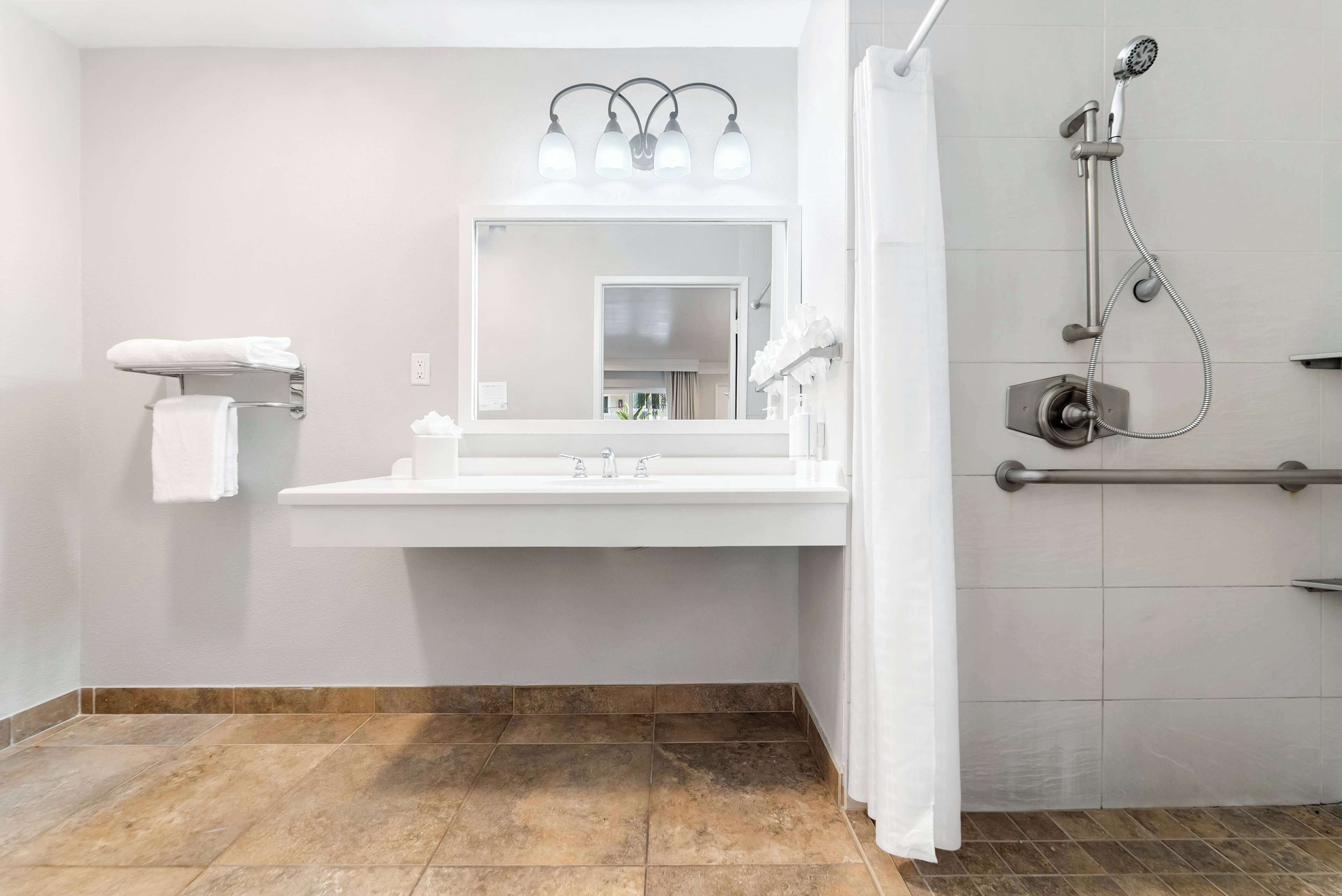 A bathroom with a white sink, mirror, and shower.