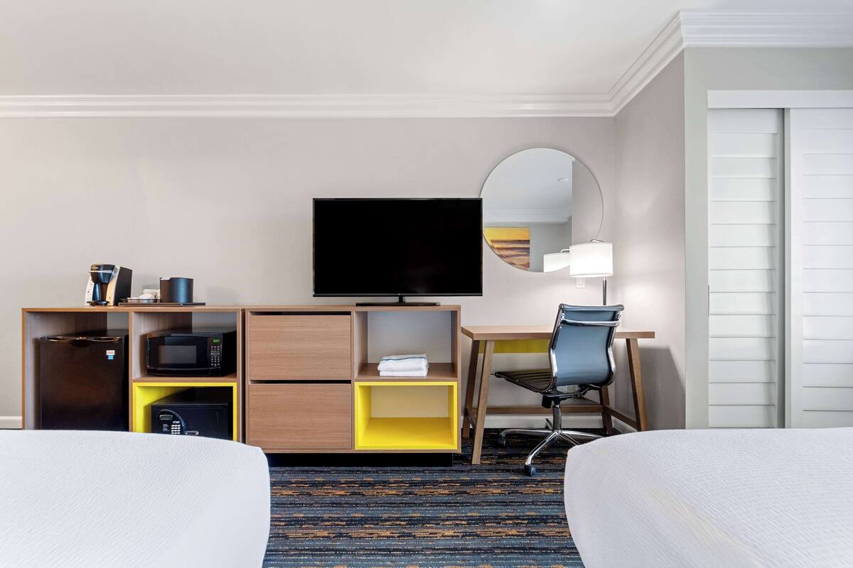 Ein Hotelzimmer mit Bett, Schreibtisch mit Stuhl, Fernseher, Mikrowelle und Safe.