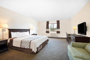 Una habitación de hotel con una cama grande, un escritorio con silla, televisión y dos lámparas.