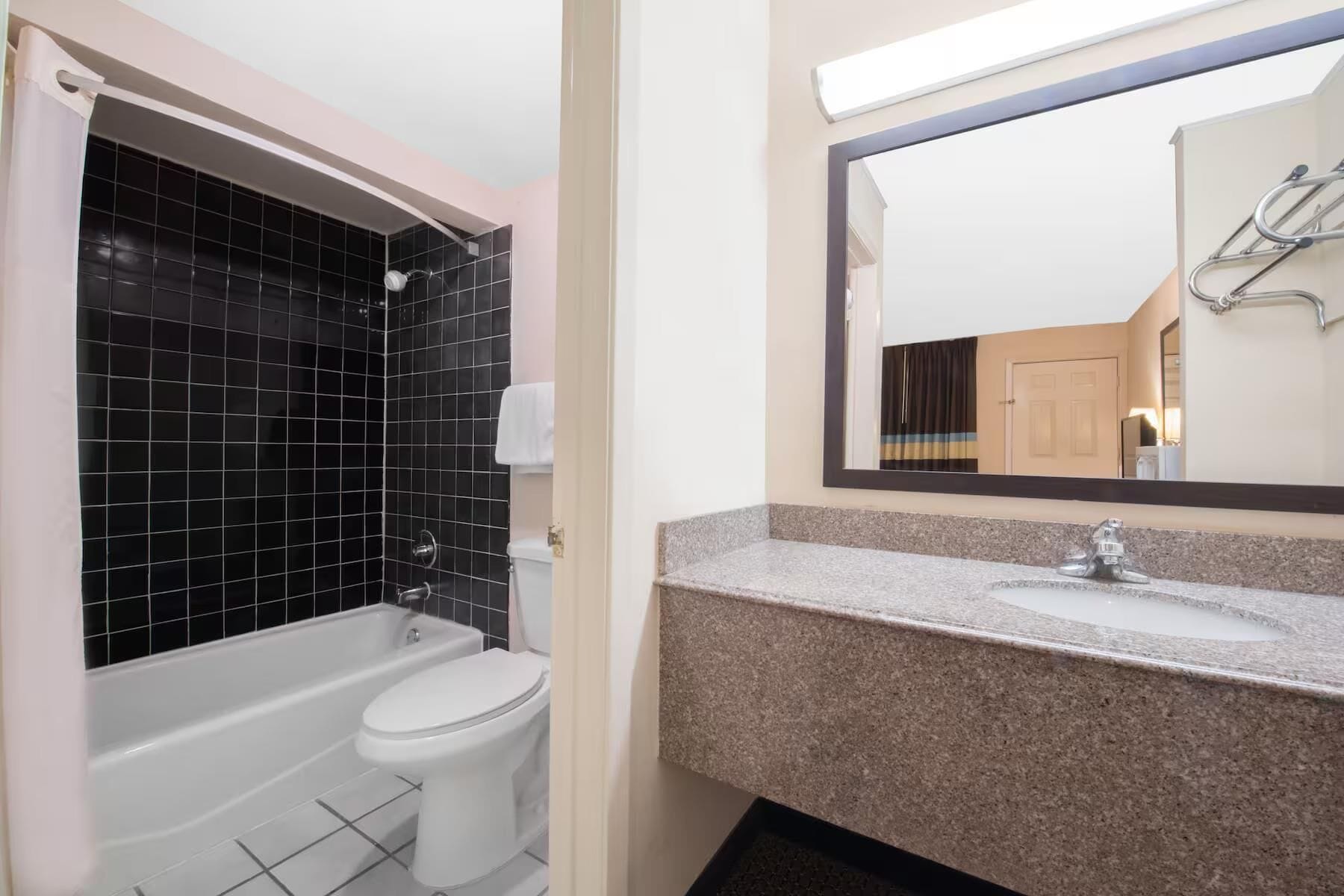 A bathroom with a bathtub, toilet, and a sink with a mirror above it.