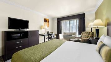 A hotel room with a bed, a desk, a chair, a television, and a window with curtains.